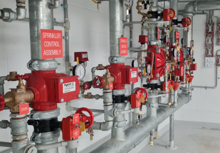 A red fire alarm switch with a warning sign on a concrete wall, highlighting safety in industrial settings.